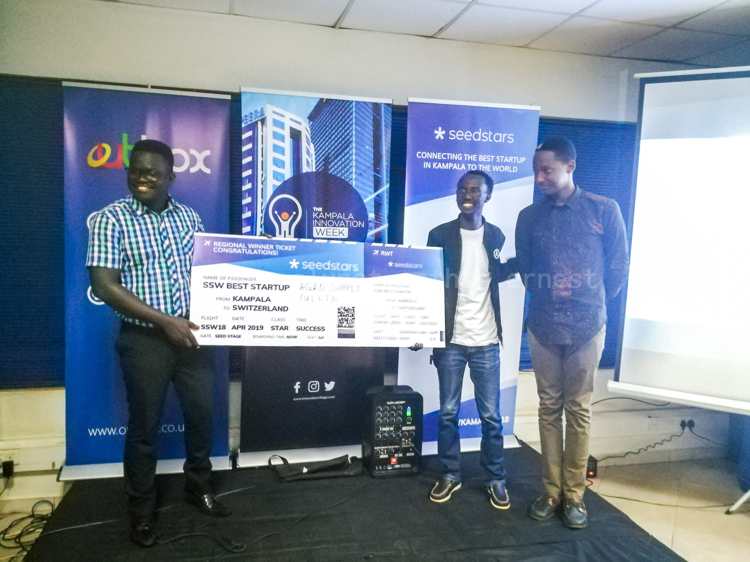 Ogwal Joseph; Founder and Chief Executive (Left), and Watson Atwine (Right; IT Specialist who represented the team, recivce their victory dummy air ticket from Herve Kubwimana, Innovation Facilitator at Merck, at the Seedstar Kampala competition at Outbox Hub on Friday 24th, August 2018.