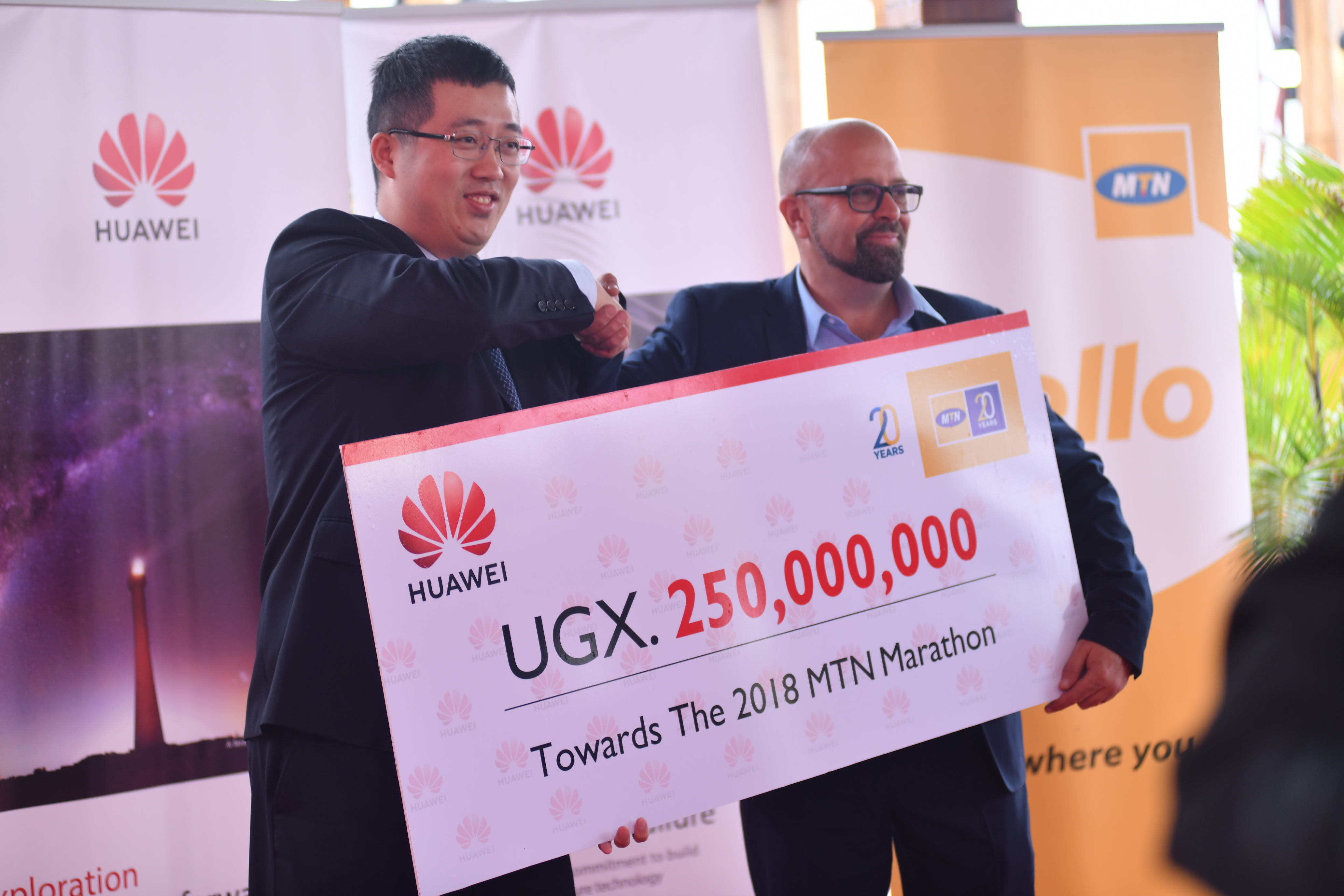 Huawei Uganda Managing Director Mr. Liujiawei hand over a dummy cheque board of Huawei's Contribution to the MTN Marathon of 250,000,000 Ugx to MTN Uganda Chief Marketing Officer Mr. Olivier Pentout.