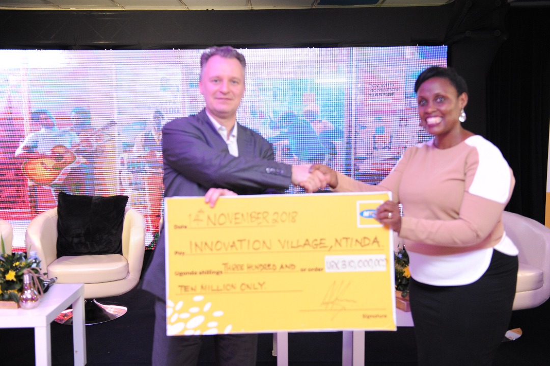 Wim Vanhelleputte CEO MTN Uganda (L) handsover a UGX310 million cheque to The Innovation Village as part of partnership that will see the telecom provide high speed internet and server for technology hub.