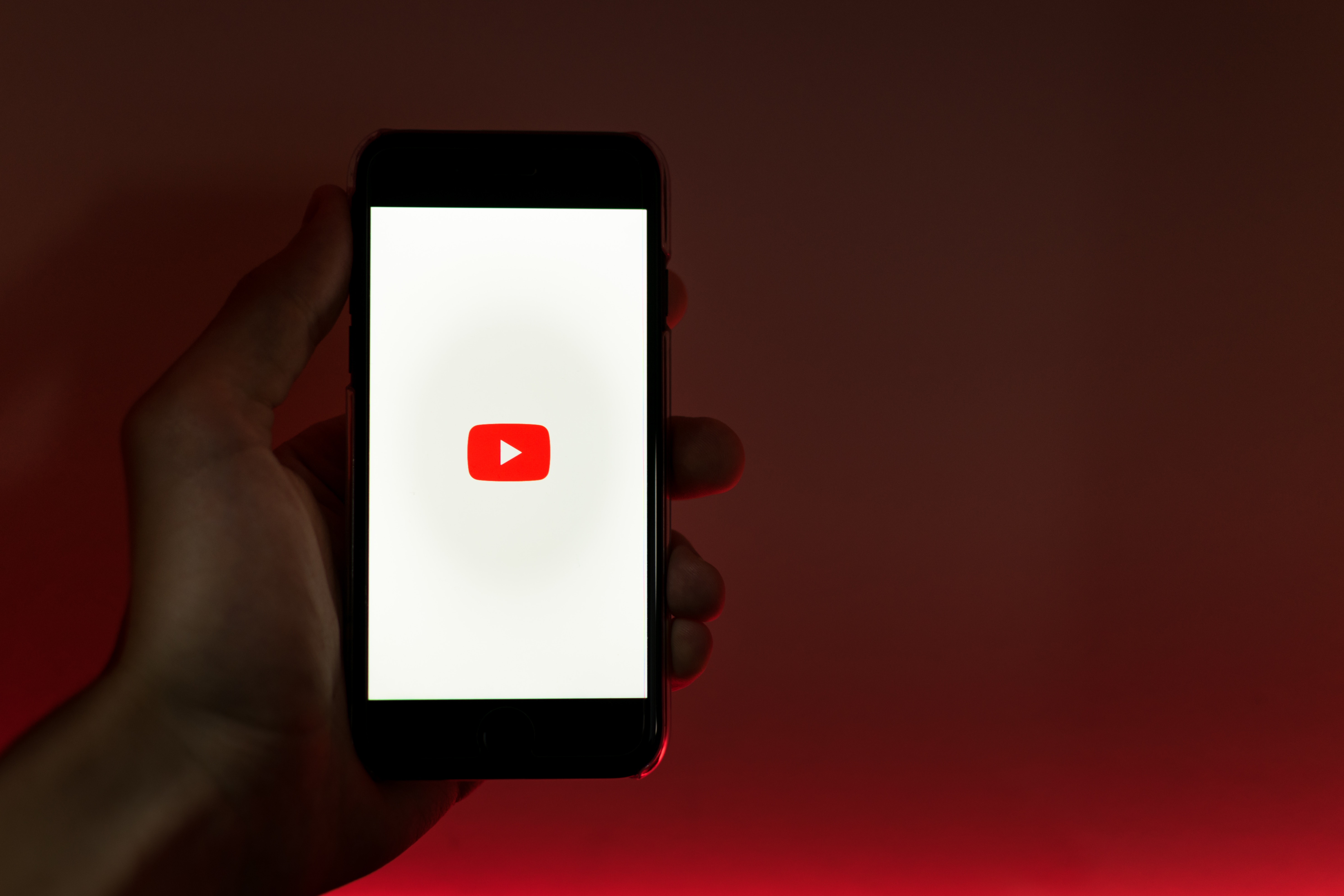 A person displaying a YouTube logo on a smartphone | Photo by Szabo Viktor on Unsplash.