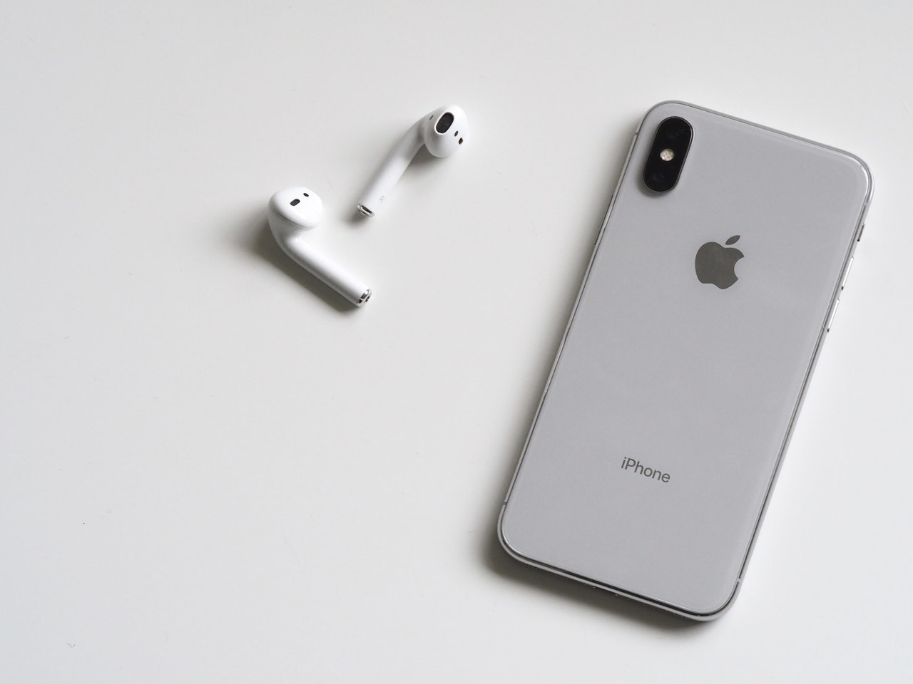A Pair of Apple's AirPods pictured next to an iPhone | Photo by Plush Design Studio from Pexels.