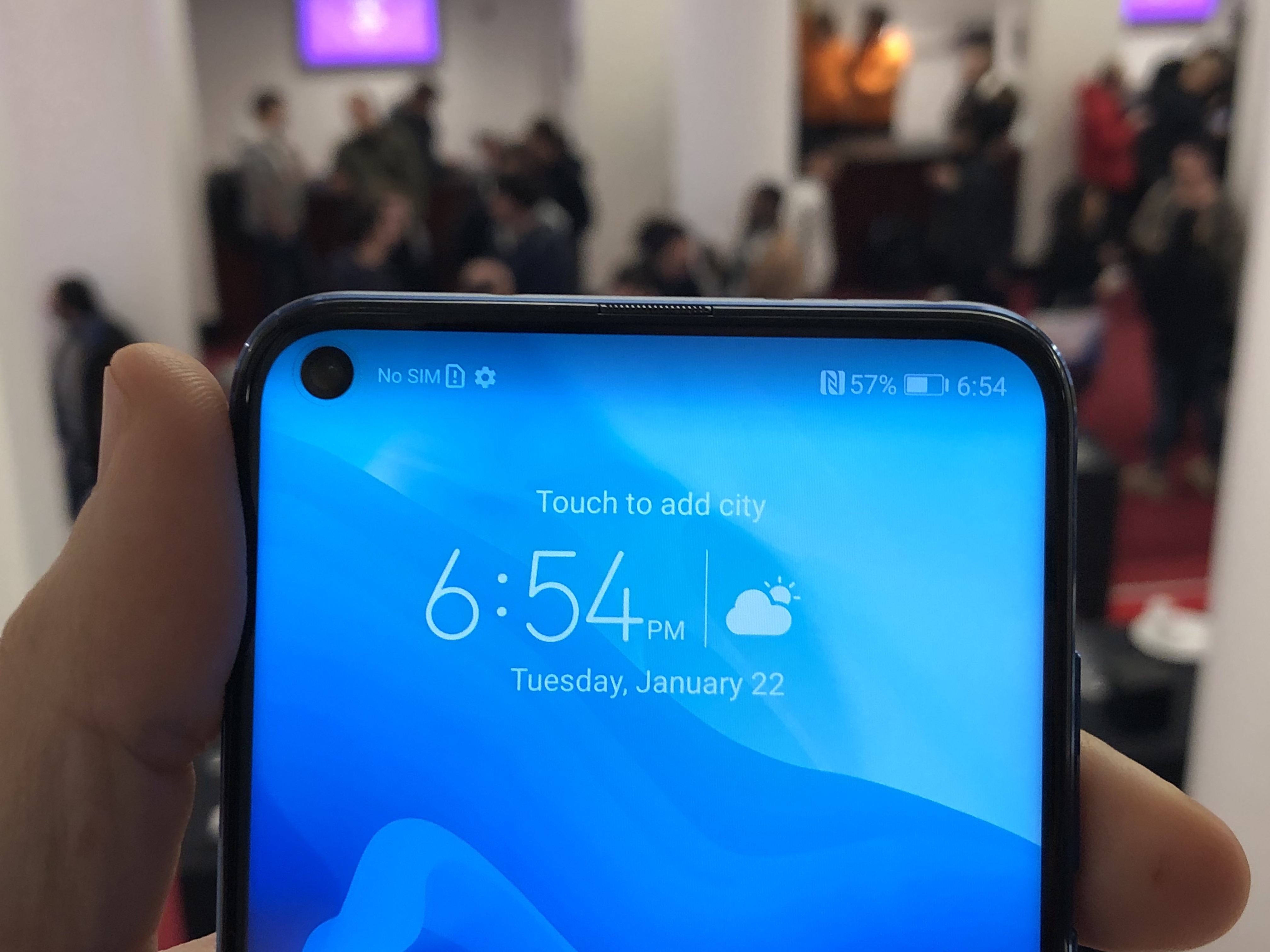 Pictured a person holding a Huawei Honor View 20 during its launch, features a hole-punched display | Photo Courtesy: TechCrunch