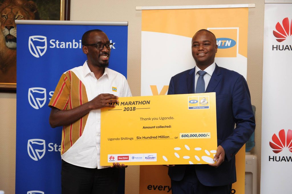  MTN Uganda's Senior Manager, Brand and Communications; Martin Sebuliba (L) and Stanbic Bank Uganda Chief Executive Officer; Patrick Mweheire (R) pictured holding a dummy thank you card showing the amount of money collected (UGX600M) from the MTN 2018 marathon.