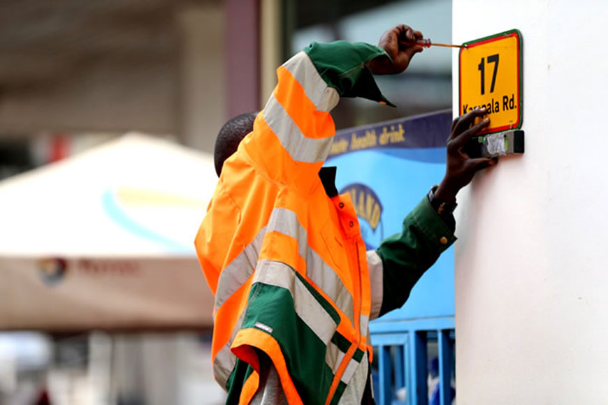 Pictured an official installing a 17th signage on a building along Kampala Road | File Photo/WatchDog Uganda.