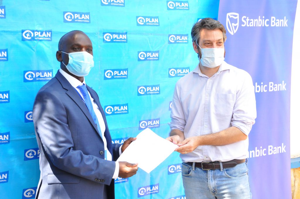 Stanbic Bank Uganda Head of Personal Markets Mr. Israel Arinaitwe (L) and Plan International's Head of Programmes Mr. Greg Lavendar (R) after signing the MoU during the prepaid cards handover ceremony.