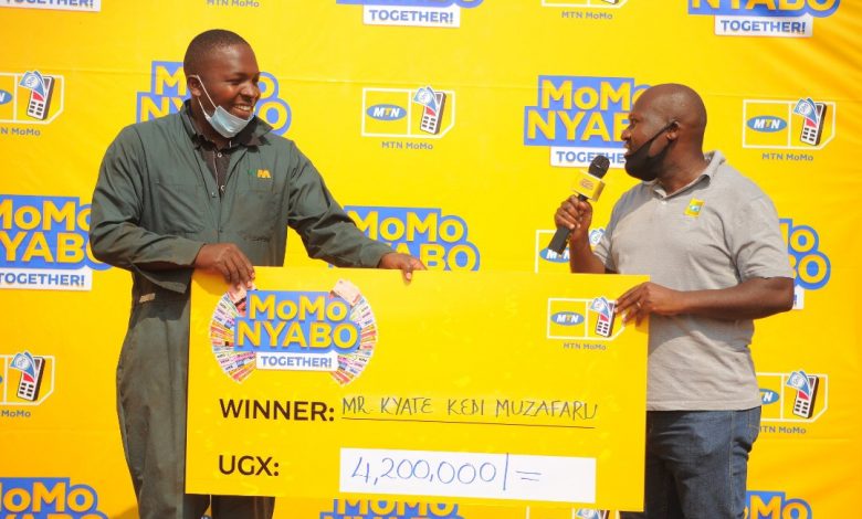 Isaiah Semamuli (R) the MTN Uganda Senior Manager Eastern Region Operations handing over a dummy cheque of UGX4.2 million to Kedi Muzafaru as a winner in the MoMoNyabo Together promo.