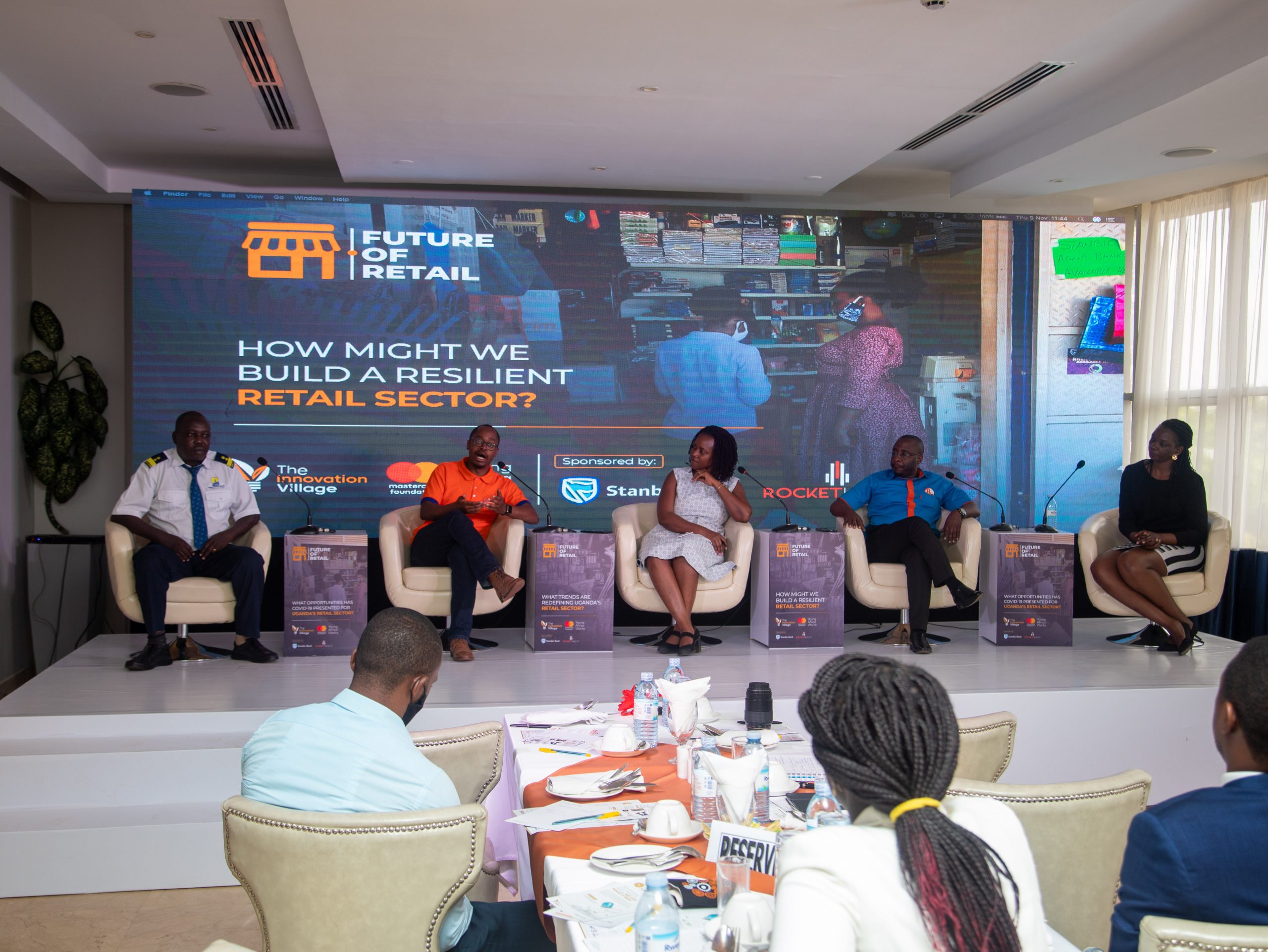 Davis Musinguzi (orange t-shirt); Managing Director of RocketHealth speaking at the launch of the Thoughts of Leadership report on the Future of Retail in Uganda at the Golden Tulip. Courtesy Photo