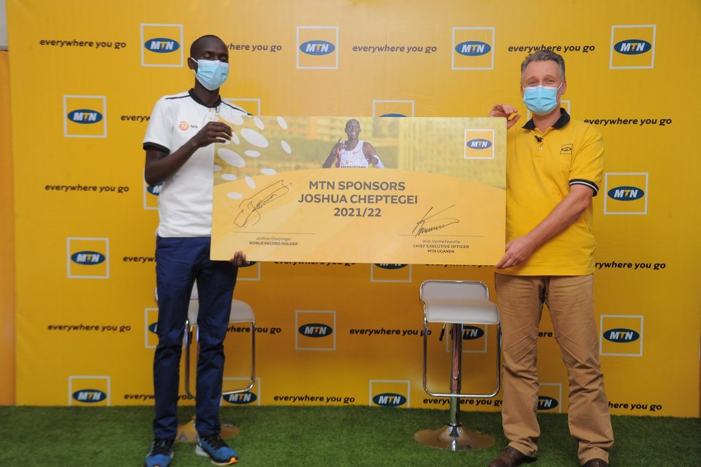 World record breaking athlete, Joshua Cheptegei (L) and MTN Uganda Chief Executive Officer, Wim Vanhelleputte (R) hold a sponsorship card after announcing a sponsorship deal at the Mbale Resort Hotel on Saturday 20th, February 2021 (COURTESY PHOTO/MTN Uganda)