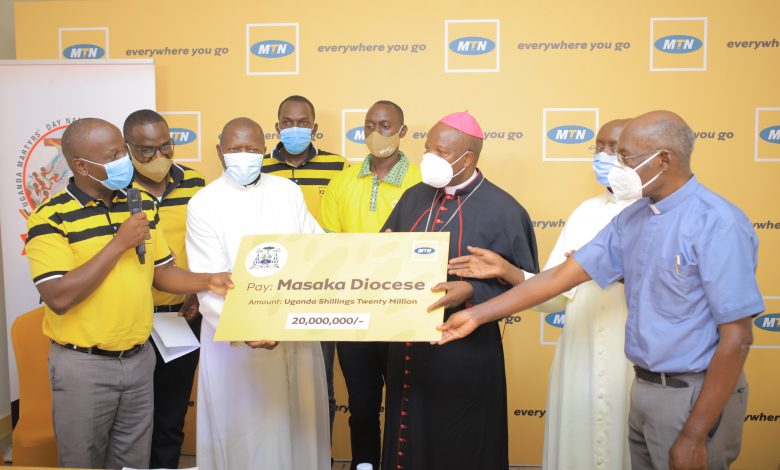 MTN Uganda General Manager of Sales and Distribution, Joseph Bogera (with microphone) hands over a cheque of UGX20 million to Masaka Catholic Diocese Bishop, Serverus Jjumba (black cope) to support the Martyrs Day preparations.