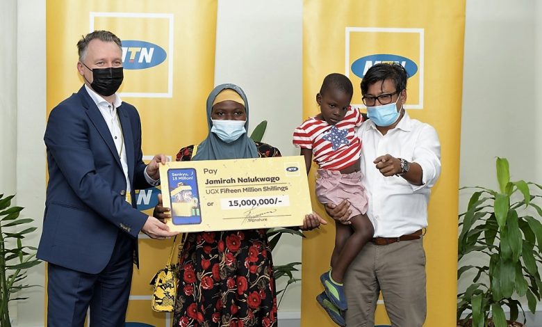 Ms. Jamirah Nalukwago (center) receives a UGX15 million dummy cheque from Wim Vanhelleputte as Somdev Sen (right) looks on.