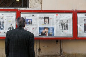 An old man pictured reading newspapers in the streets. (PHOTO: Filip Mishevski/Unsplash)