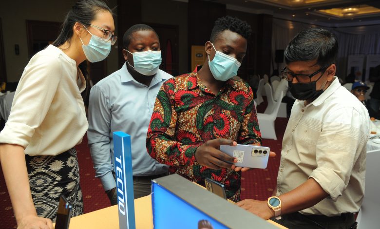 Gladys Lui (extreme left); Tecno Uganda Marketing Manager, Mark Mutungi; Vivo Energy Uganda Brand Manager Fuels (second left), and Somdev Sen; MTN Uganda Chief Marketing Officer (extreme right) taking a close look on how the Camon 18 looks like at a launch in Kampala.