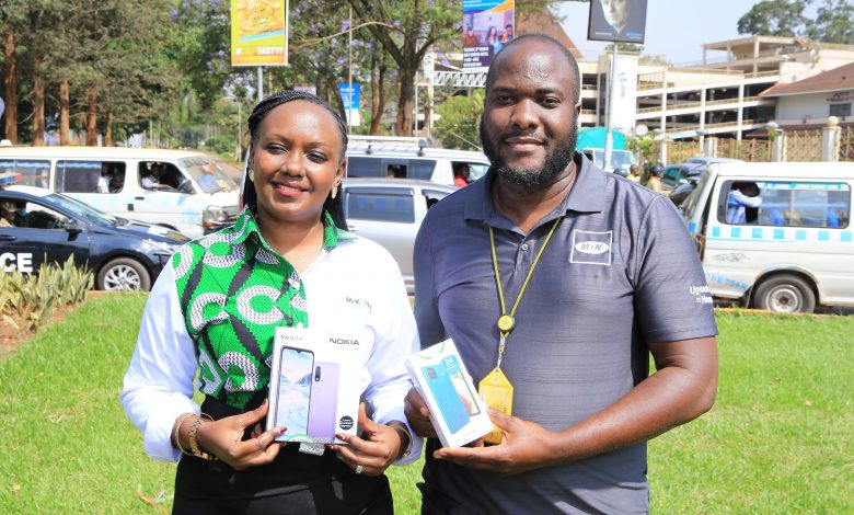 M-KOPA Spokeswoman, Brenda Nambalirwa (L) and MTN Uganda High-Value Segment Marketing Manager, Ian Mugambe display some of the phones that people can get from the Pay Mpolampola scheme.