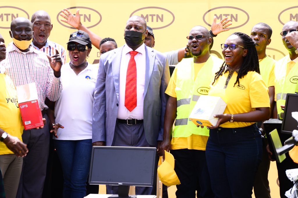 Dorcas Batwala Muhwezi (R); the MTN Uganda General Manager, Customer experience and Kenneth Kiddu (2R) handed over the computers and a WiFi router to the Principal of UICT Fred Kitogo.