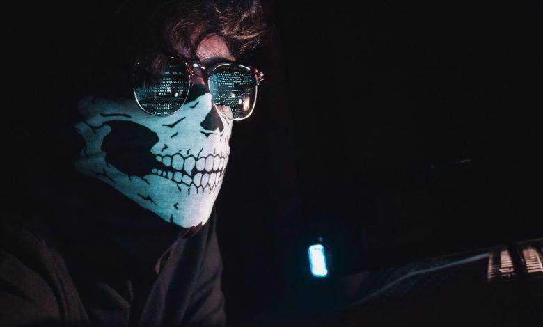 A hacker in a dark room with a covered face typing away at a computer trying to steal personal information or hack into a system is a cybersecurity threat. PHOTO: Nahel Abdul Hadi/Unsplash