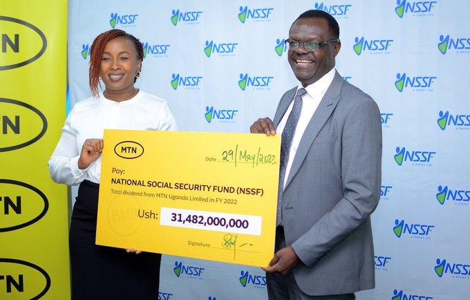 MTN Uganda CEO Sylvia Mulinge (L) handing over a dummy cheque of UGX31.482 billion to NSSF acting MD Patrick Ayota a total dividend from MTN Uganda in financial year 2022.