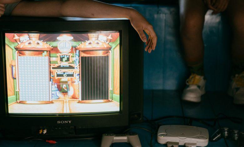 Pictured a person leaning on a TV displaying visual of a game. PHOTO: Cottonbro Studio / Pexels