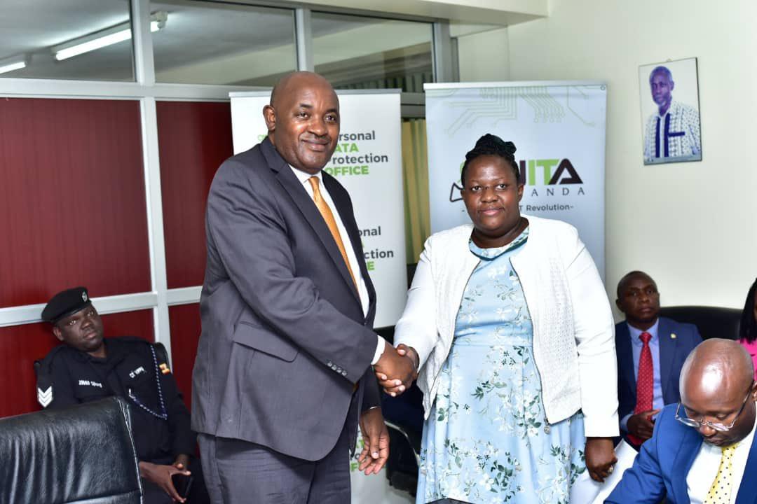 Minister of ICT and National Gudiance, Hon. Chris Baryomunsi (left) congratulating Prof. Annabella Habinka Basaza Ejiri, NITA-U Board member.