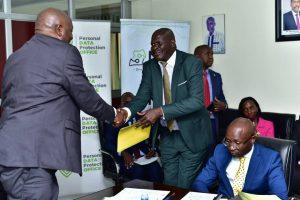 Minister of ICT and National Gudiance, Hon. Chris Baryomunsi (left) congratulating Julius Otai, new NITA-U Board member.