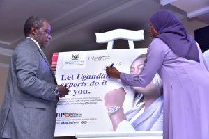 Permanent Secretary for the Ministry of ICT and National Guidance, Dr. Aminah Zawedde (right) signing on a cardboard of the National BPO Policy as Prof. William Bazeyo, Chairman of the BPO Council looks on, after the launch of the National Business Process Outsourcing (BPO) Policy and Publicity Campaign at Mestil Hotel. PHOTO: Ministry of ICT