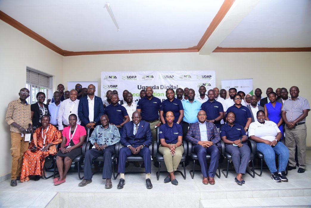 Regina Kimera (seated - center), Amaruma Manza Vincent (4th from left), and Roger Kaija Irumba (3rd from right) pose for a group photo with representatives from NITA-U, the Ministry of ICT & National Guidance, the Office of the Prime Minister, UNHCR, the National Environmental Management Authority, and local government leaders. COURTESY PHOTO
