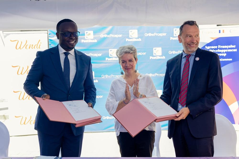 PostBank Uganda Managing Director, Julius Kakeeto (left) and Marc Trouyet, the Country Director for AFD in Uganda exchange MoUs as H.E. Virginie Leroy (C), Ambassador of France to Uganda looks, after they announced their partnership. COURSTESY PHOTO
