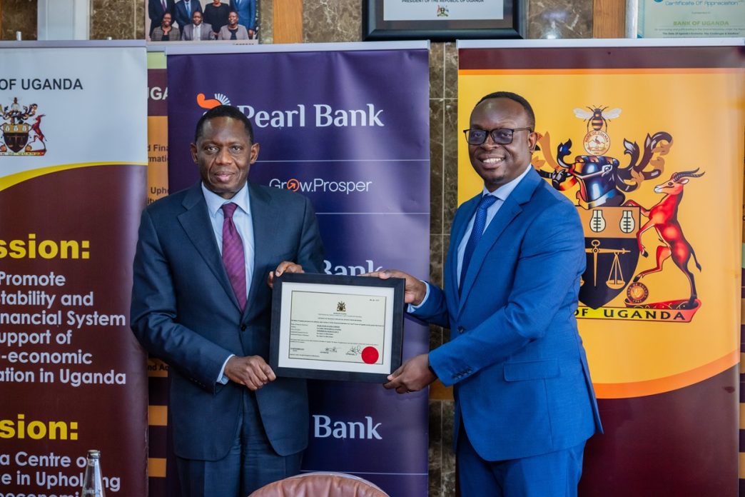 Bank of Uganda Governor, Dr. Michael Atingi-Ego (left) handing over an operating license to Pearl Bank Uganda's Managing Director, Mr. Julius Kakeeto (right). COURTESY PHOTO