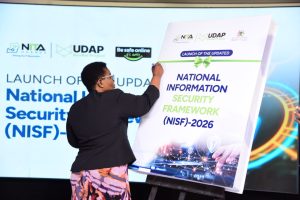 Rt. Hon. Justine Kasule Lumumba, Minister of ICT and National Guidance, signs on a board signaling the launch of the updated National Information Security Framework (NISF) 2026. COURTESY PHOTO