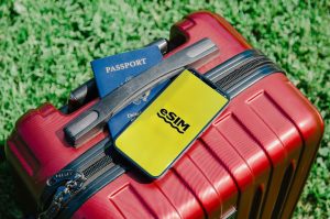 Close-up of a red suitcase with a smartphone displaying eSIM and a passport, symbolizing travel readiness. PHOTO: Jacob/via Pexels