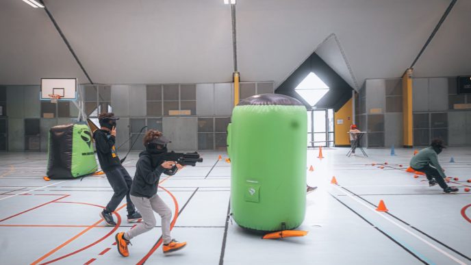 Energetic teenagers playing an indoor laser tag game with vibrant inflatables and obstacles. PHOTO: Newman Photographs/via Pexels